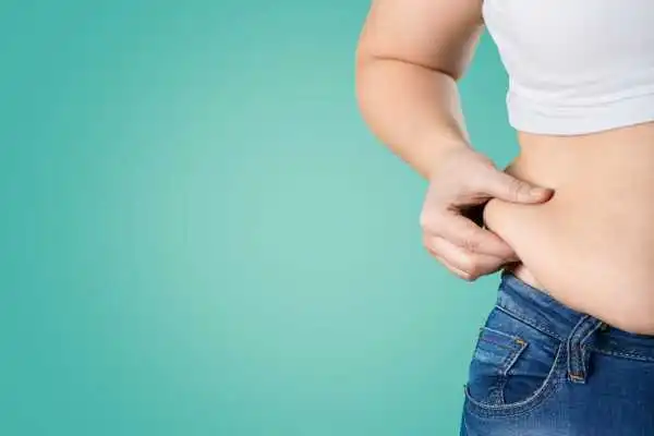 Image of woman pinching her love handles to show weight gain Birmingham